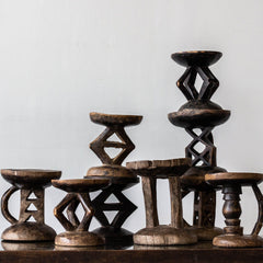 Set of wooden stools with intricate designs on a plain background