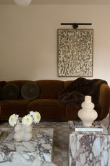 Living room with brown sofa, marble coffee table, and abstract wall art.