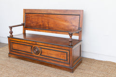 Wooden bench with backrest on a beige rug against a white wall