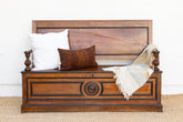 Wooden bench with decorative elements, pillows, and a blanket on a white background
