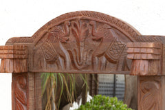 Wooden arch with carvings of animals and birds, blurred cityscape in the background