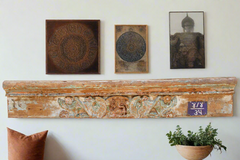 Decorative wall shelf with framed art and a plant against a white wall.