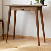 Wooden table with a white mug and books on a light wooden floor.