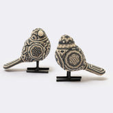 Two decorative bird figurines on stands against a white background