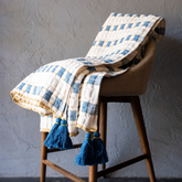 Indra handwoven cotton Sujani throw in warm cream, indigo blue, and muted mustard with oversized blue corner tassels