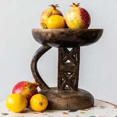 Wooden bowl with pomegranates and lemons on a patterned surface