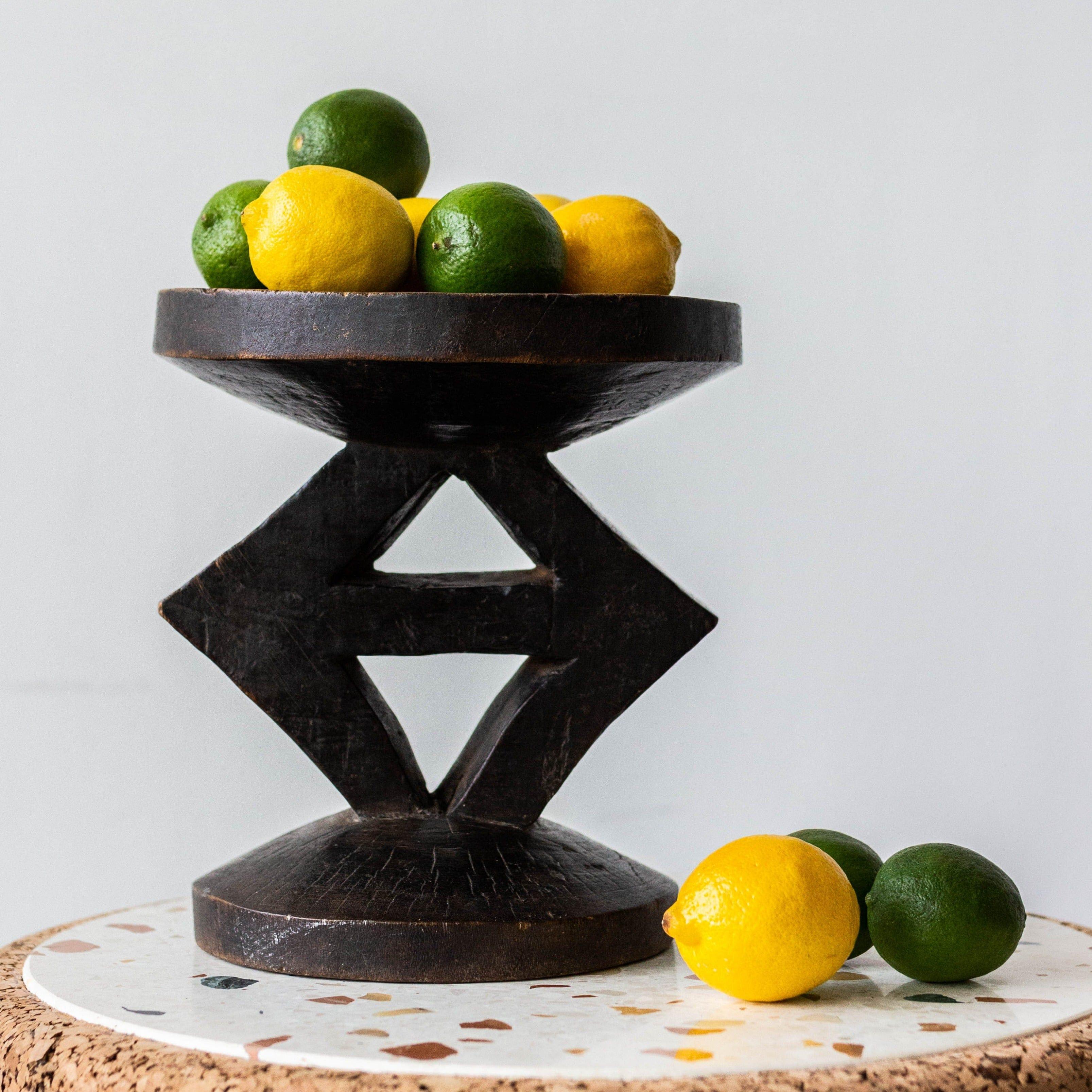 Decorative black metal stand with lemons and limes on a light background