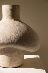 Stone sculpture resembling a human torso on a neutral background