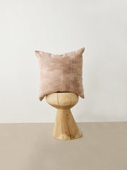 Pink pillow on a wooden stool against a white wall
