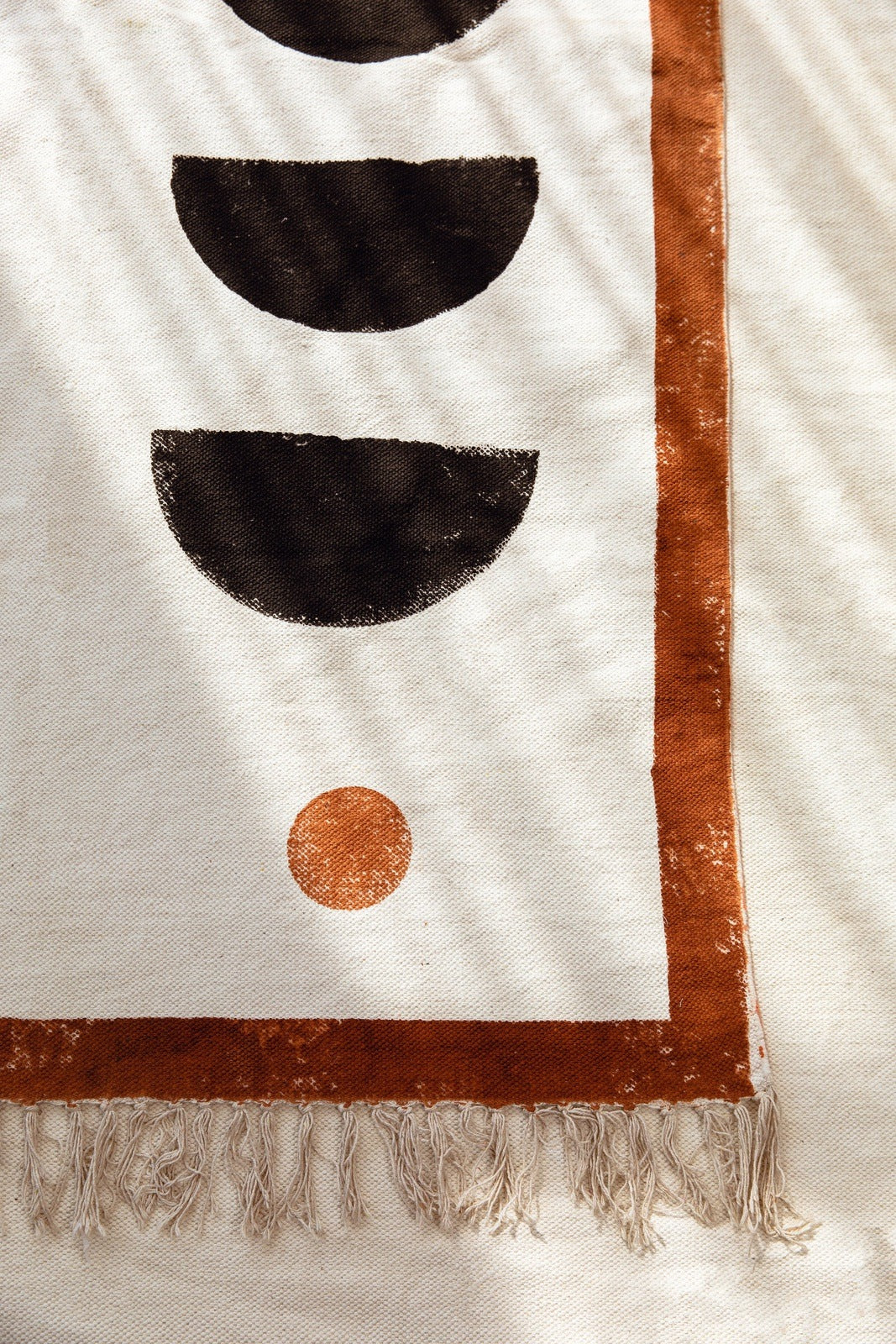 Textile with geometric patterns and fringes on a beige background