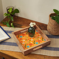 Wooden tray with floral fabric on a table with plants and a book