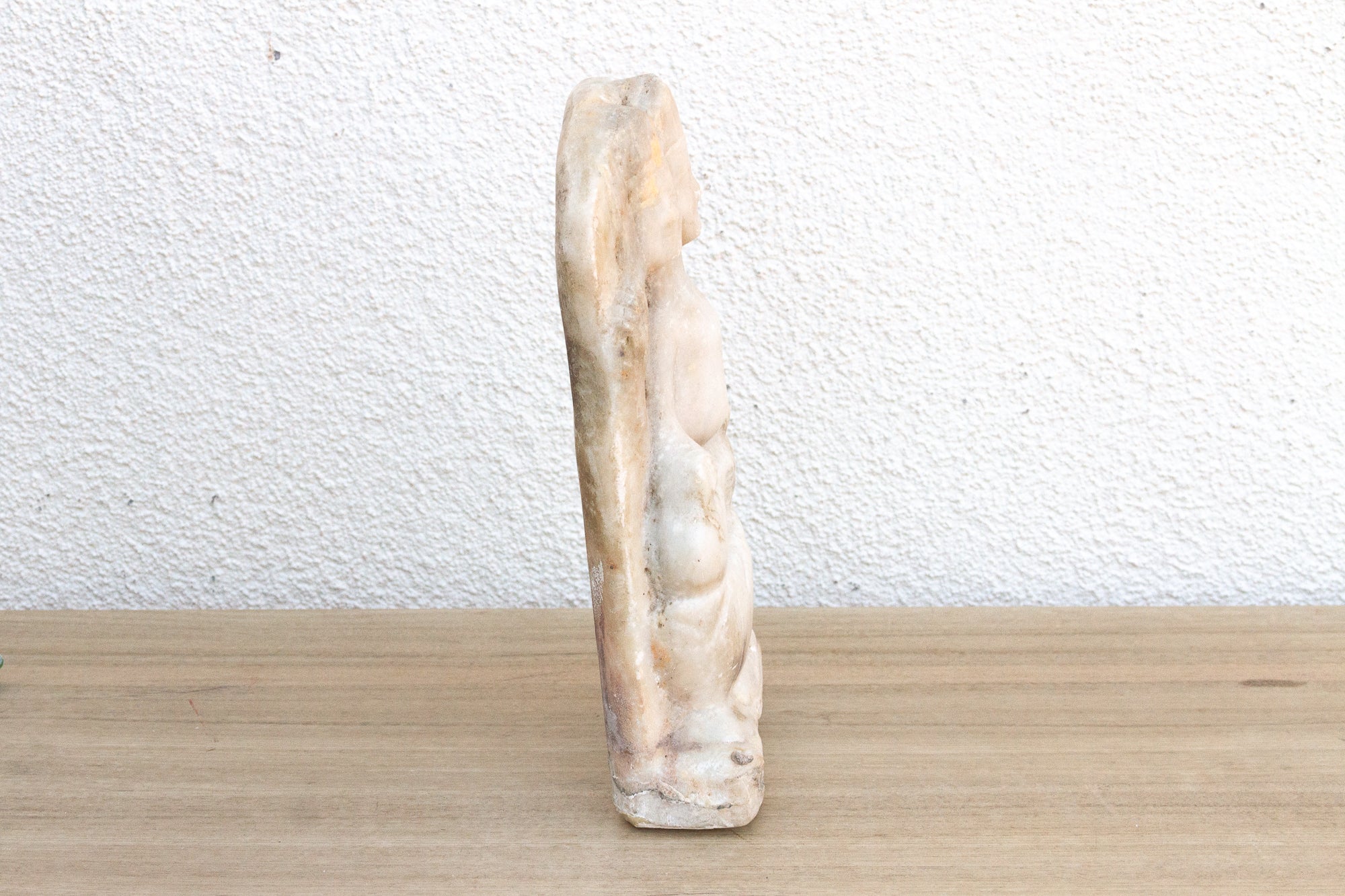 Decorative stone sculpture on a wooden surface with a white wall background
