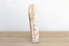 Decorative stone sculpture on a wooden surface with a white wall background