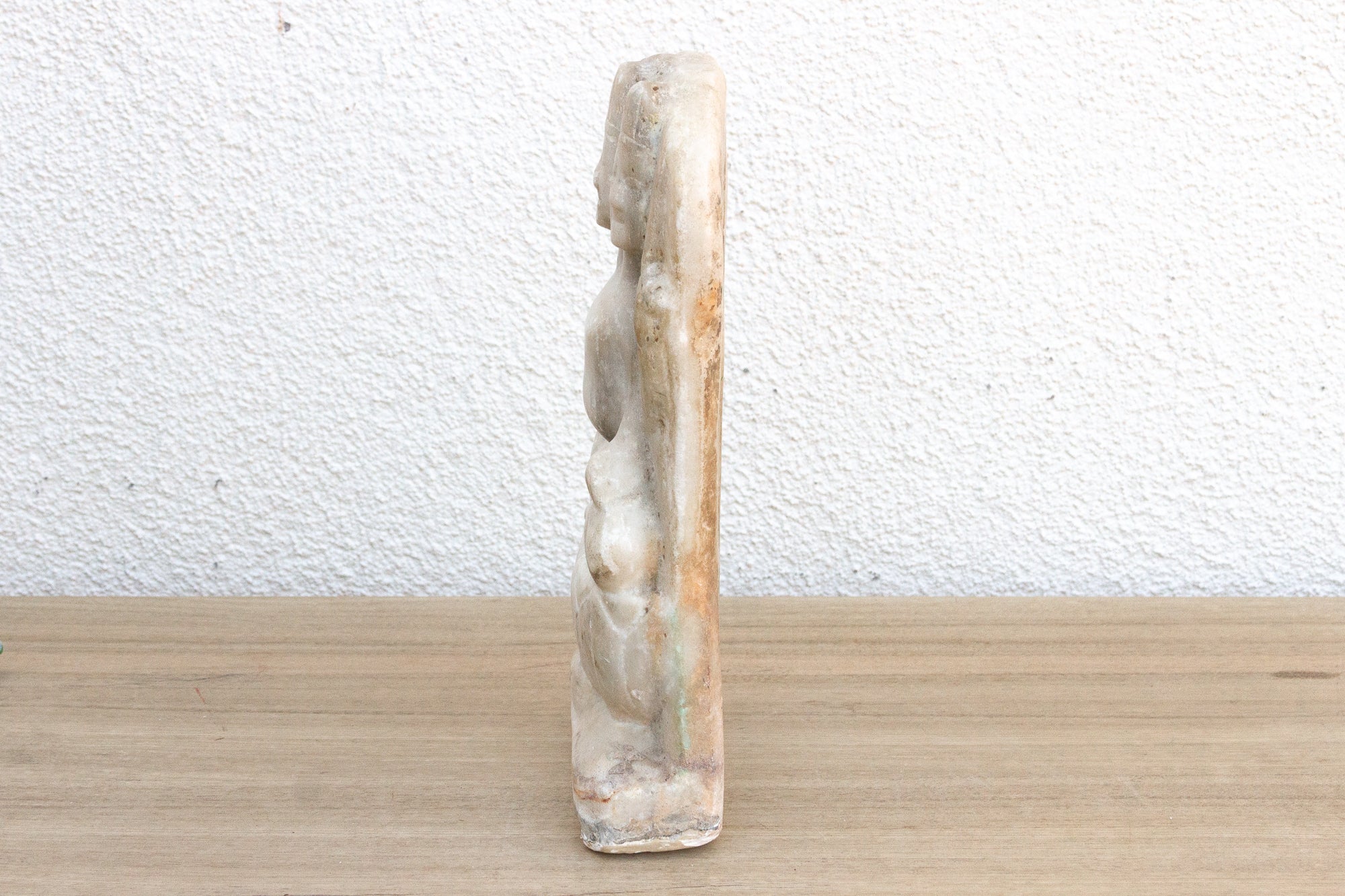 Small stone sculpture of a figure on a textured surface
