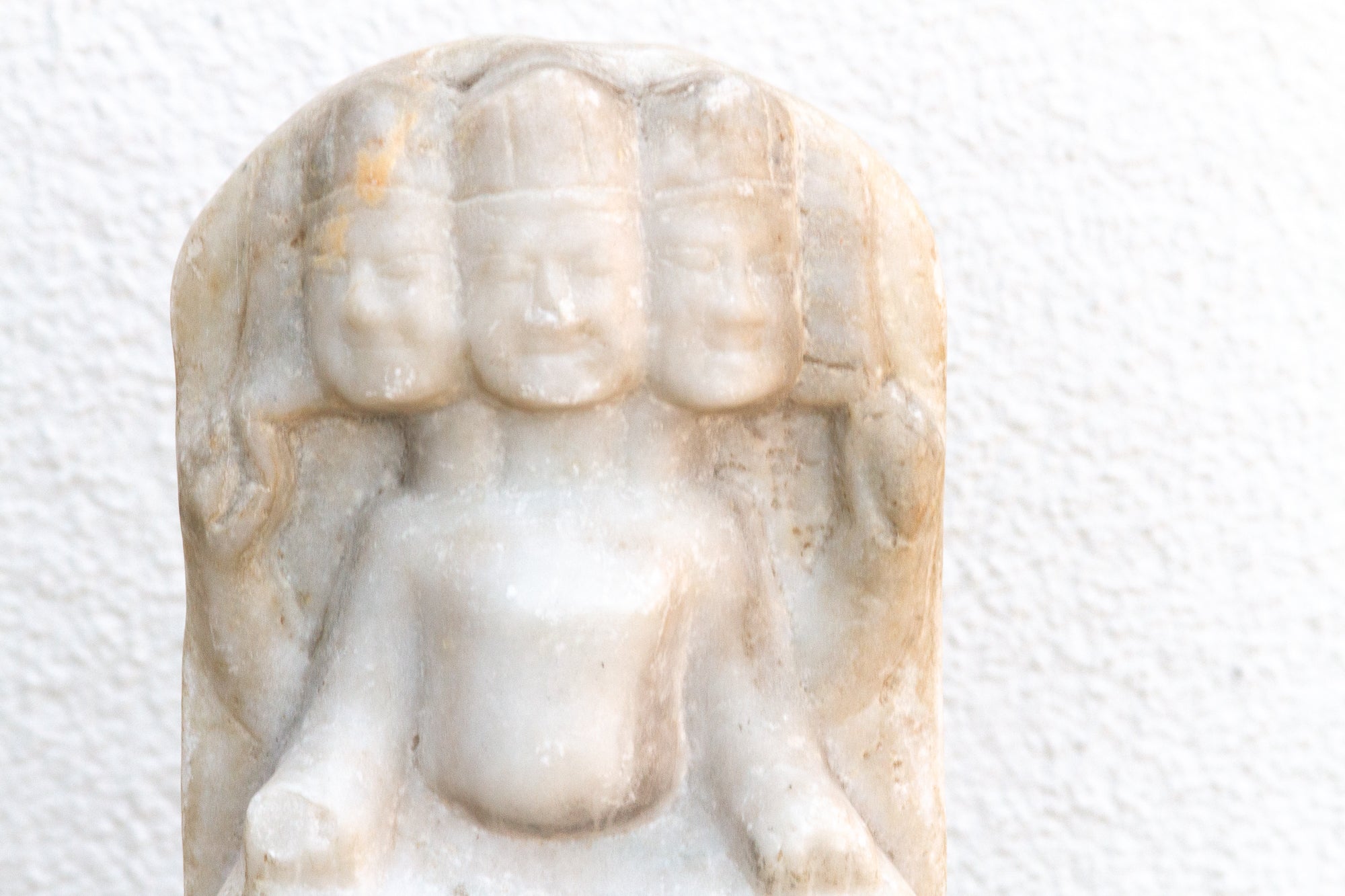 Small stone statue of a seated figure on a white background