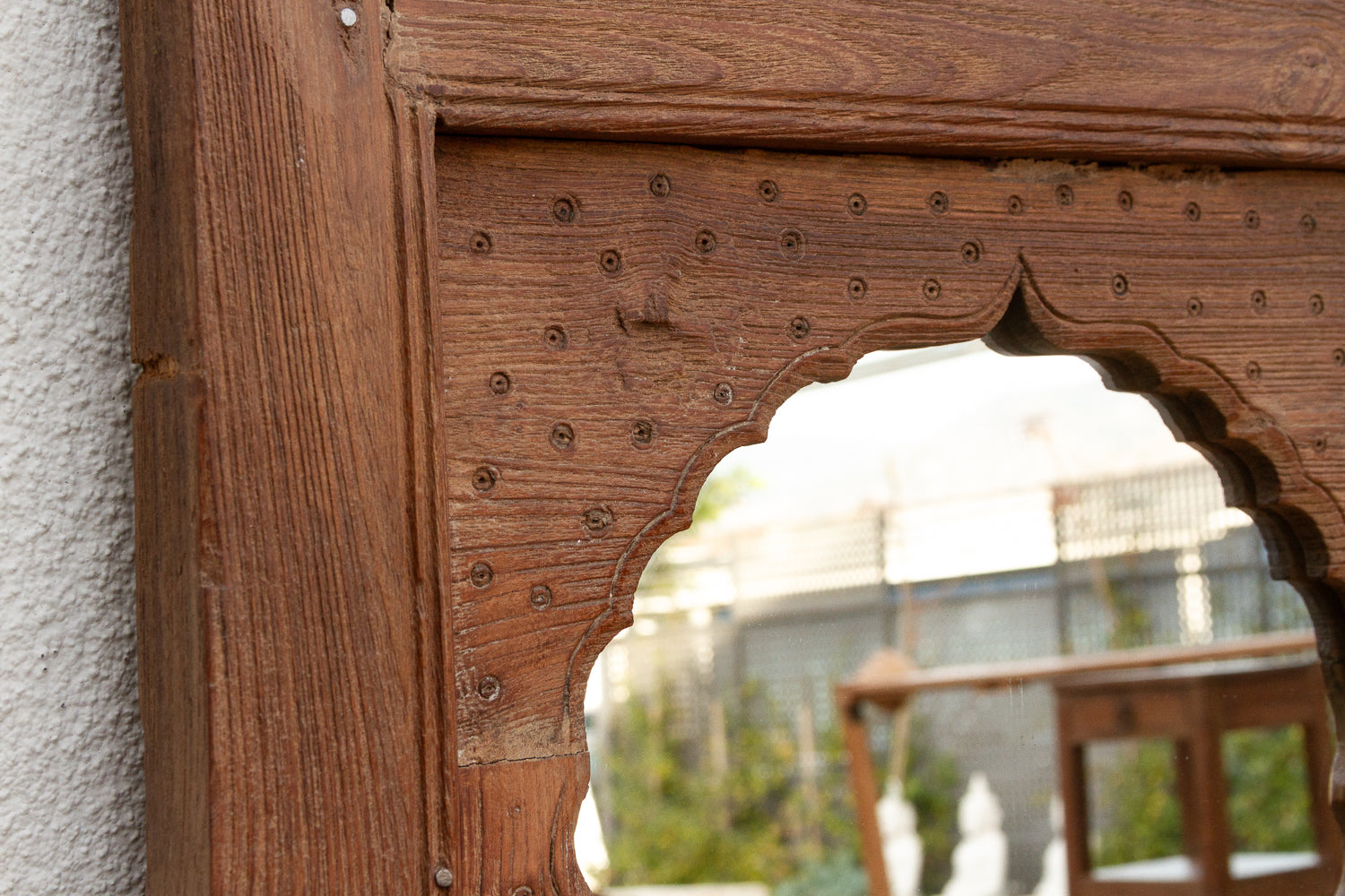 Wooden mirror frame with decorative design on a textured wall
