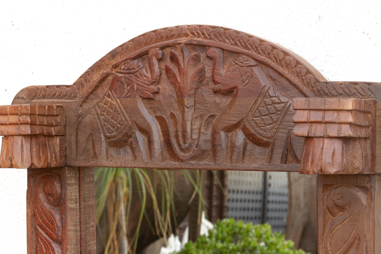 Wooden arch with carvings of animals and birds, blurred cityscape in the background