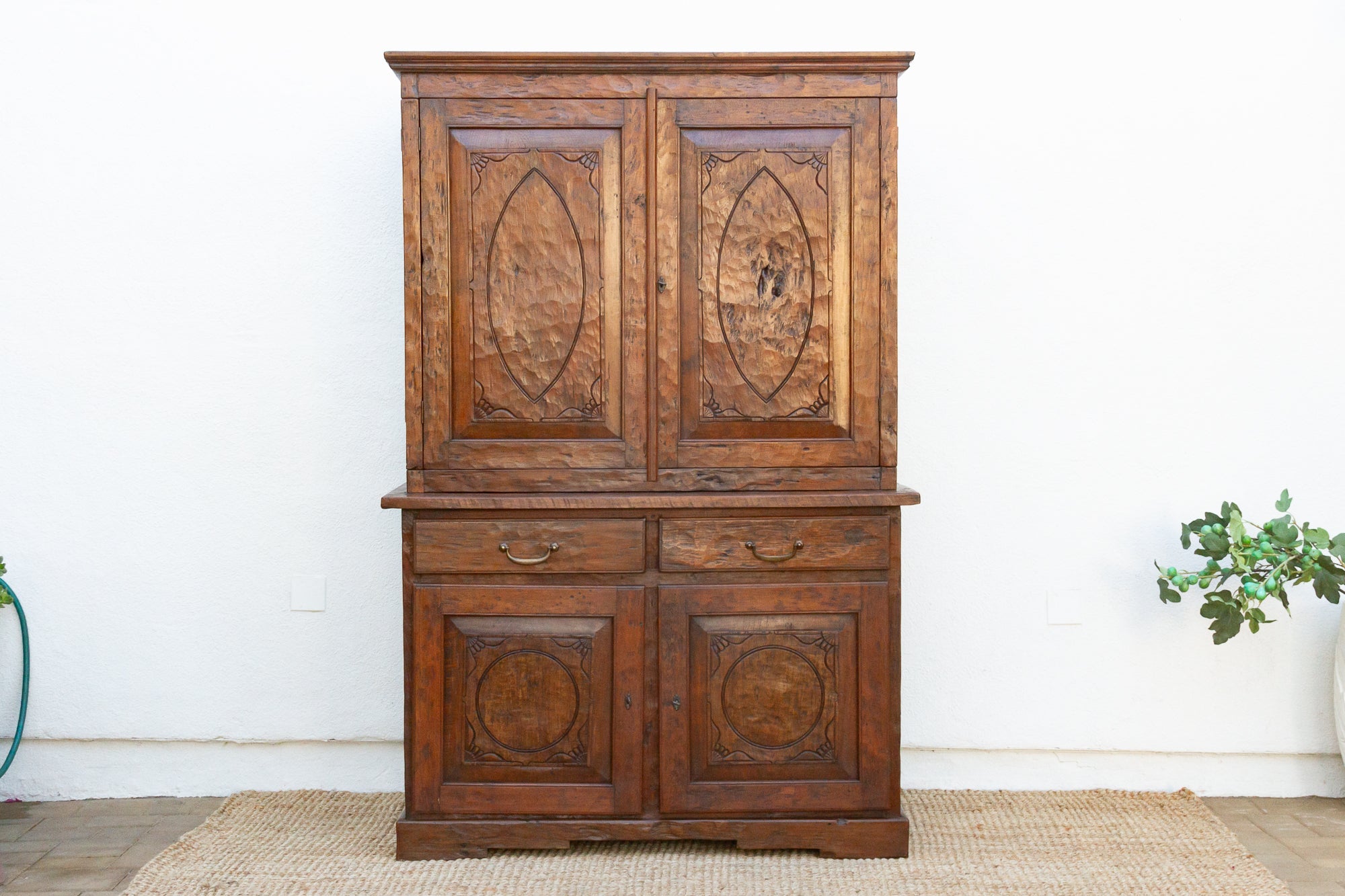 Vintage wooden cabinet with intricate carvings on a white wall.