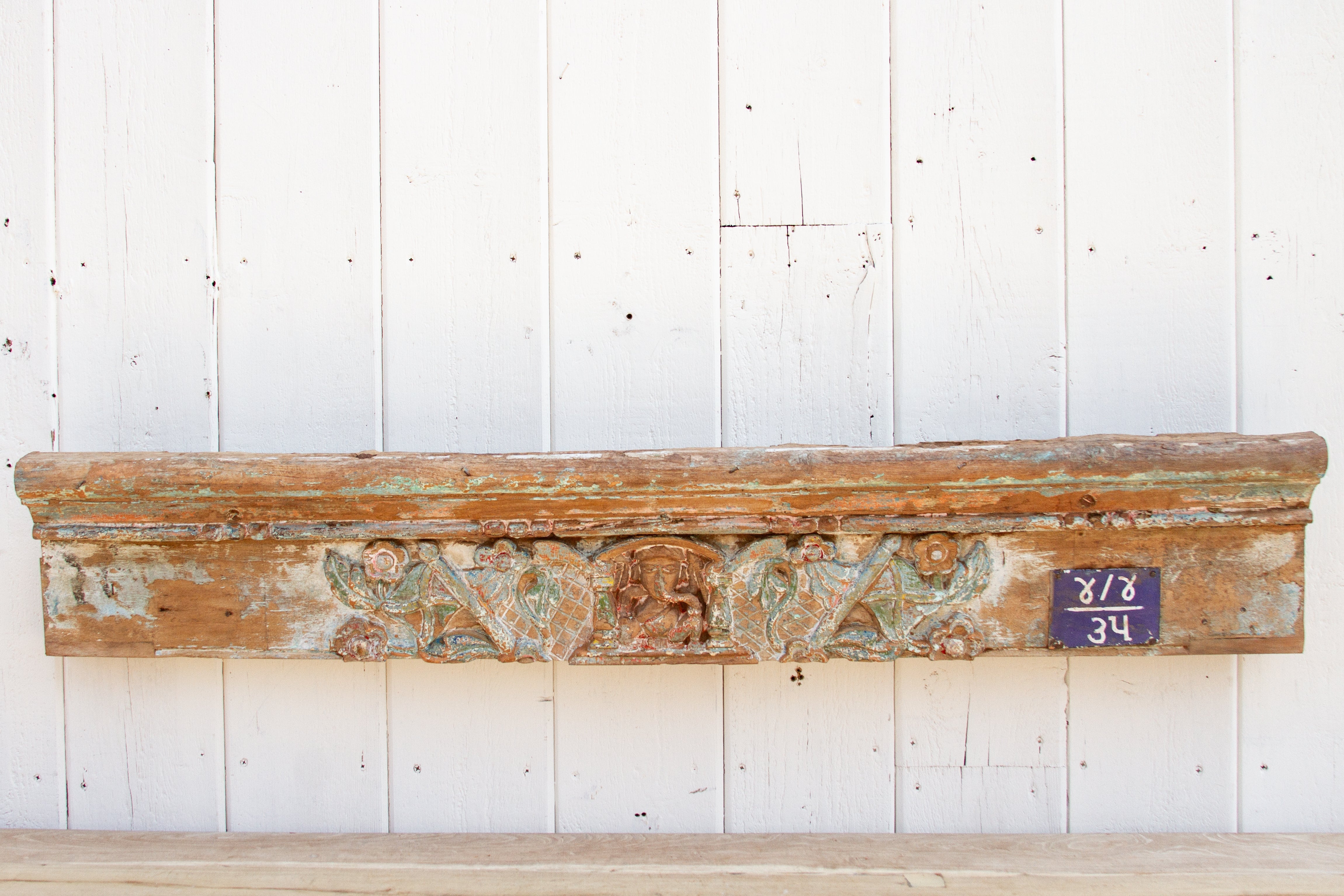 Decorative wooden mantel with carvings on a white paneled wall