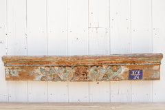 Decorative wooden mantel with carvings on a white paneled wall