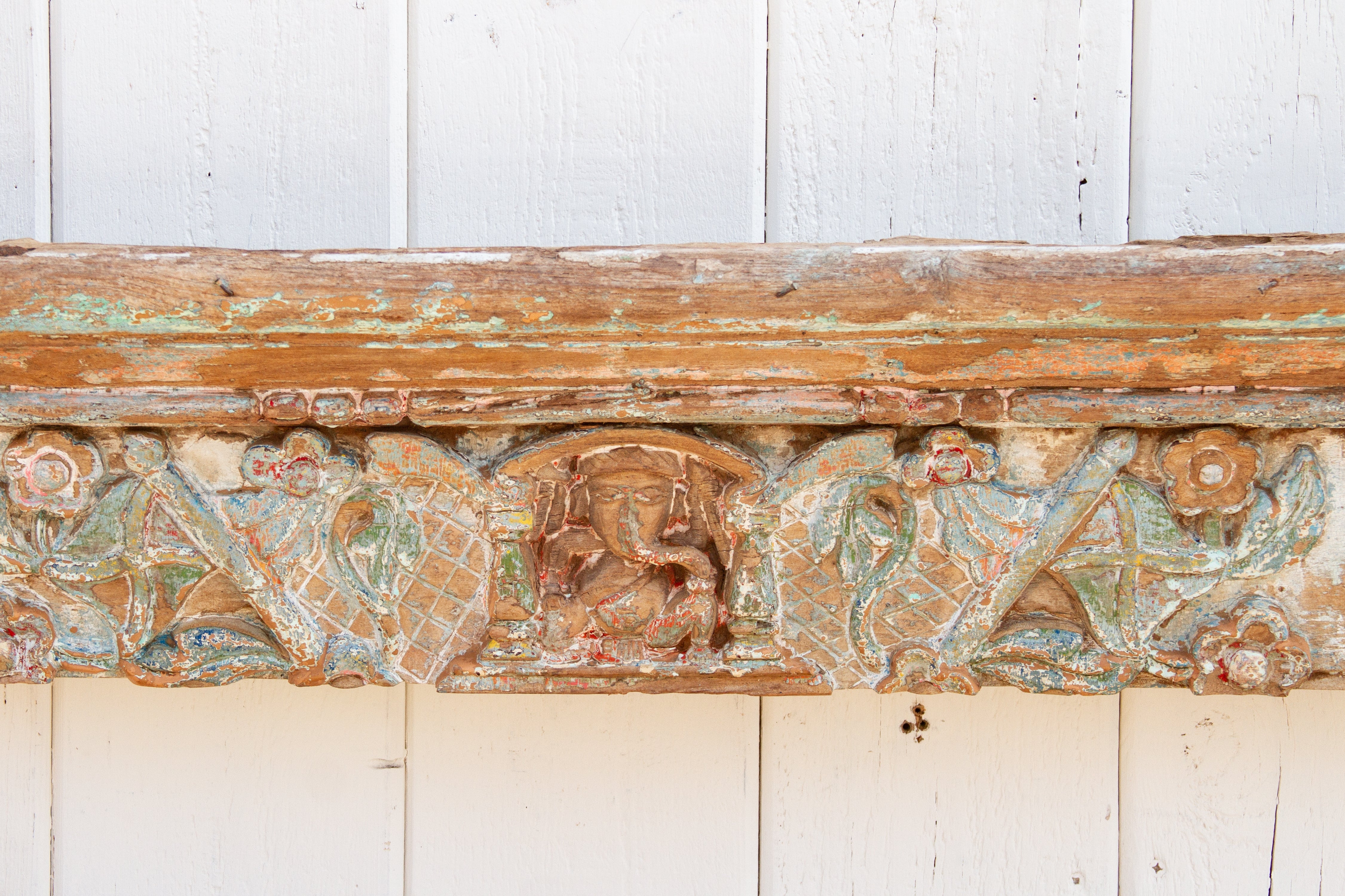 Decorative wooden panel with intricate carvings on a white wooden background