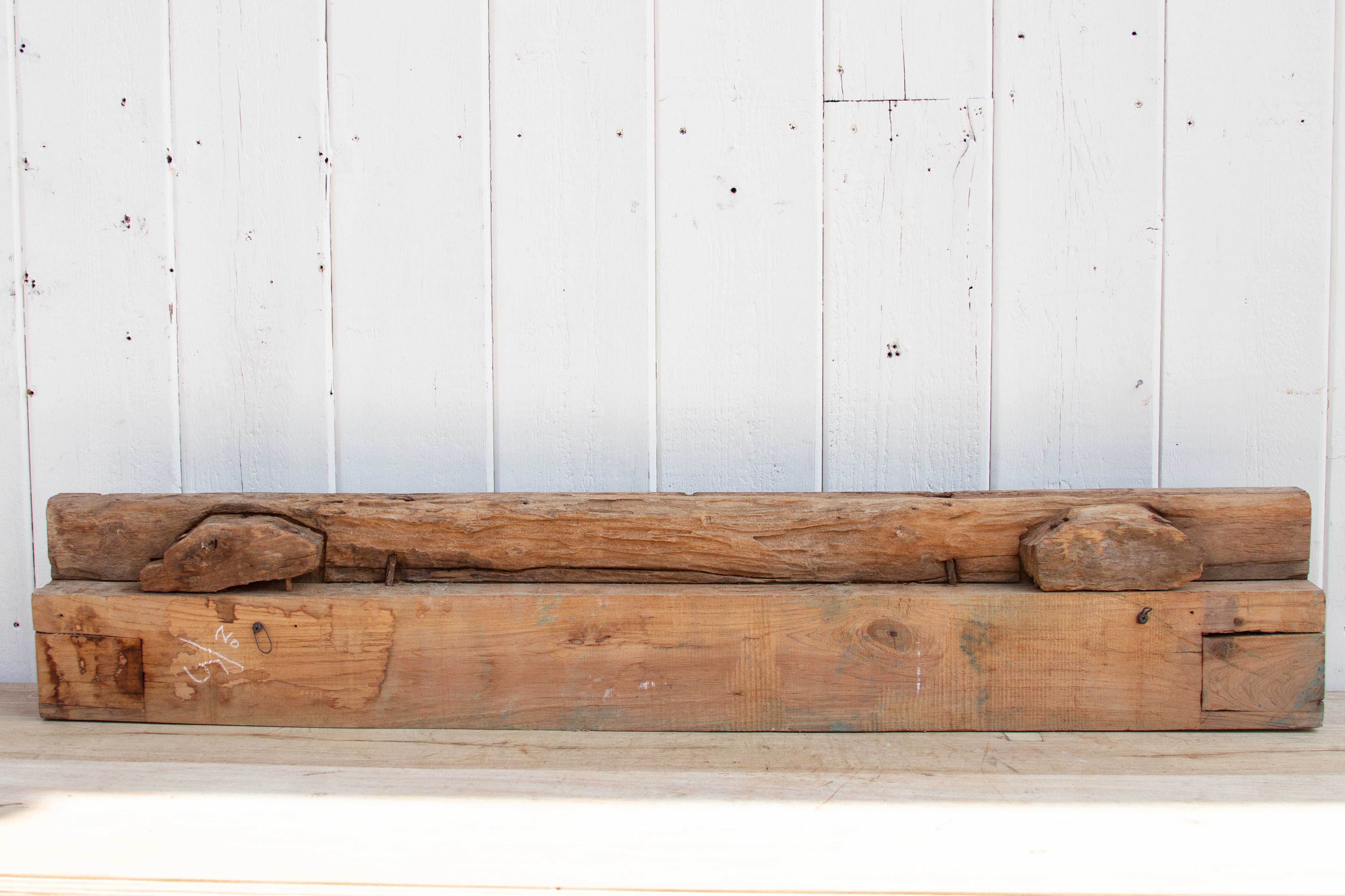 Long wooden bench against a white paneled wall