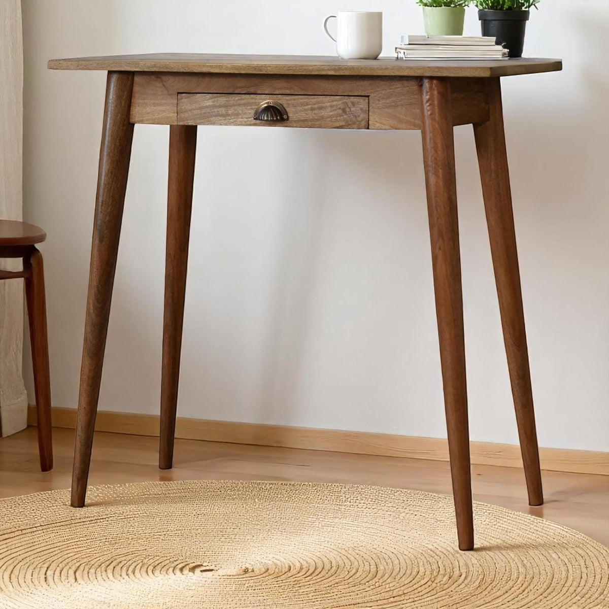 Wooden table with a white mug and books on a light wooden floor.
