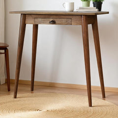 Wooden table with a white mug and books on a light wooden floor.