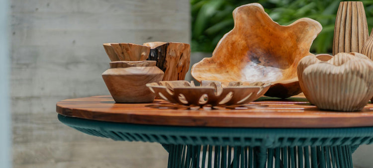 Wooden bowls and vases on a round wooden table with a blurred natural background