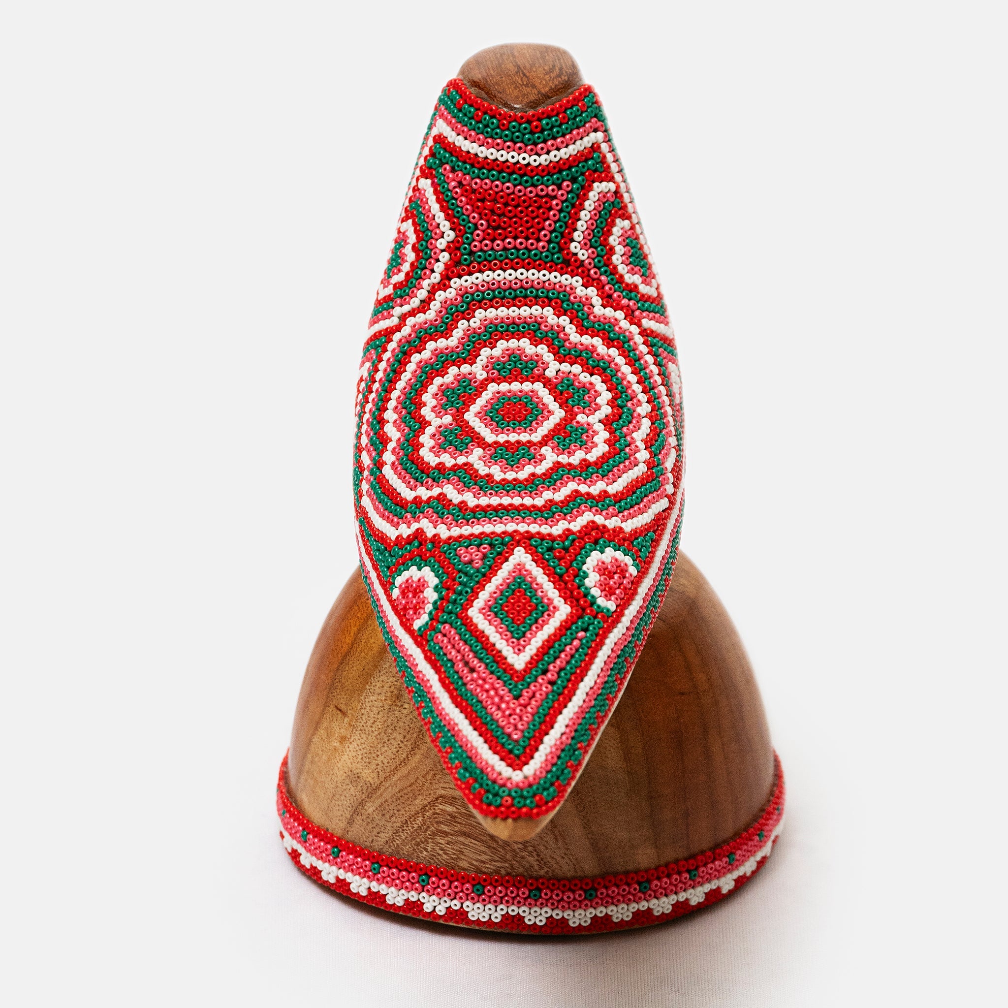 Decorative wooden object with red and green beadwork on a white background