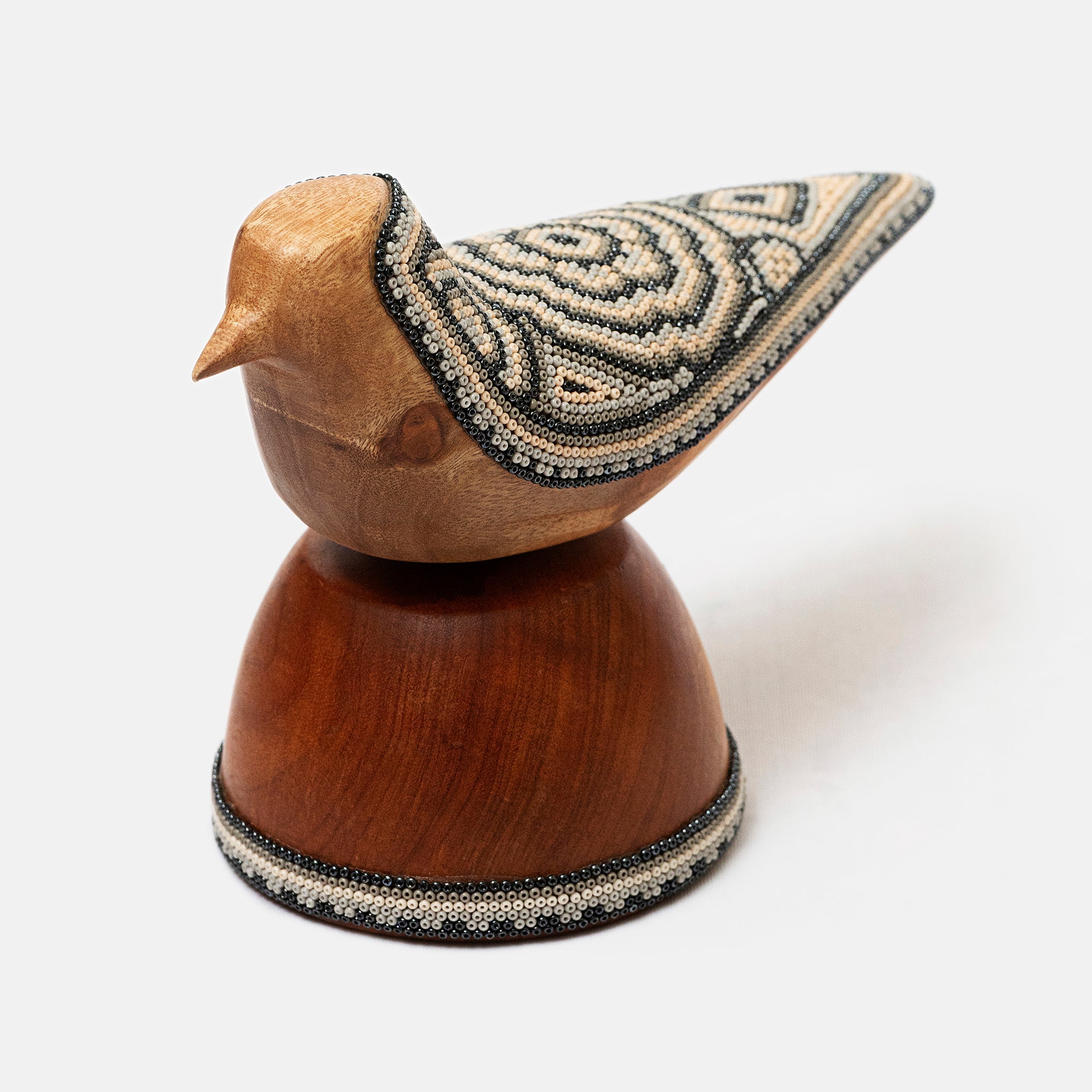 Wooden bird figurine with beaded details on a white background