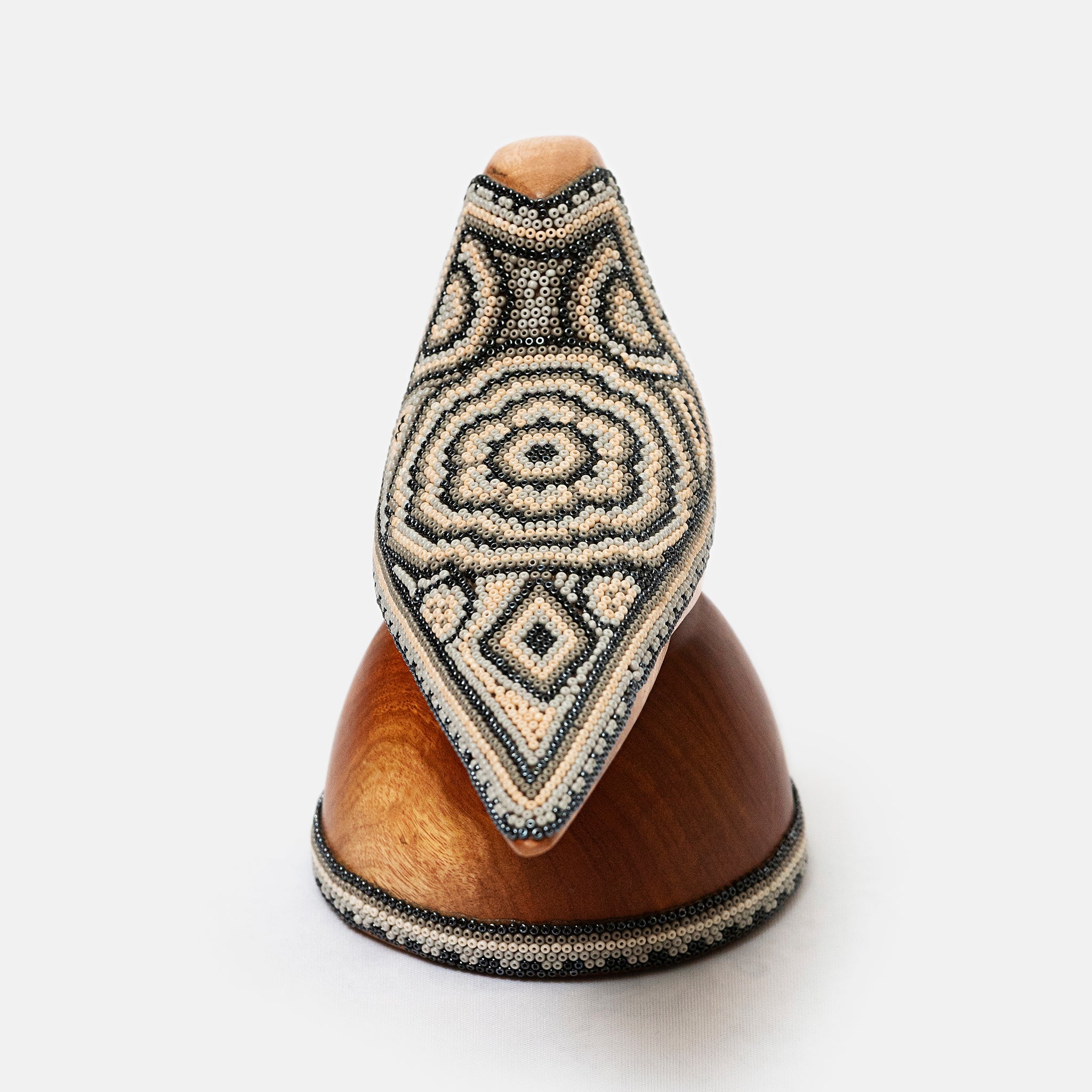 Decorative wooden object with geometric bead pattern on a white background