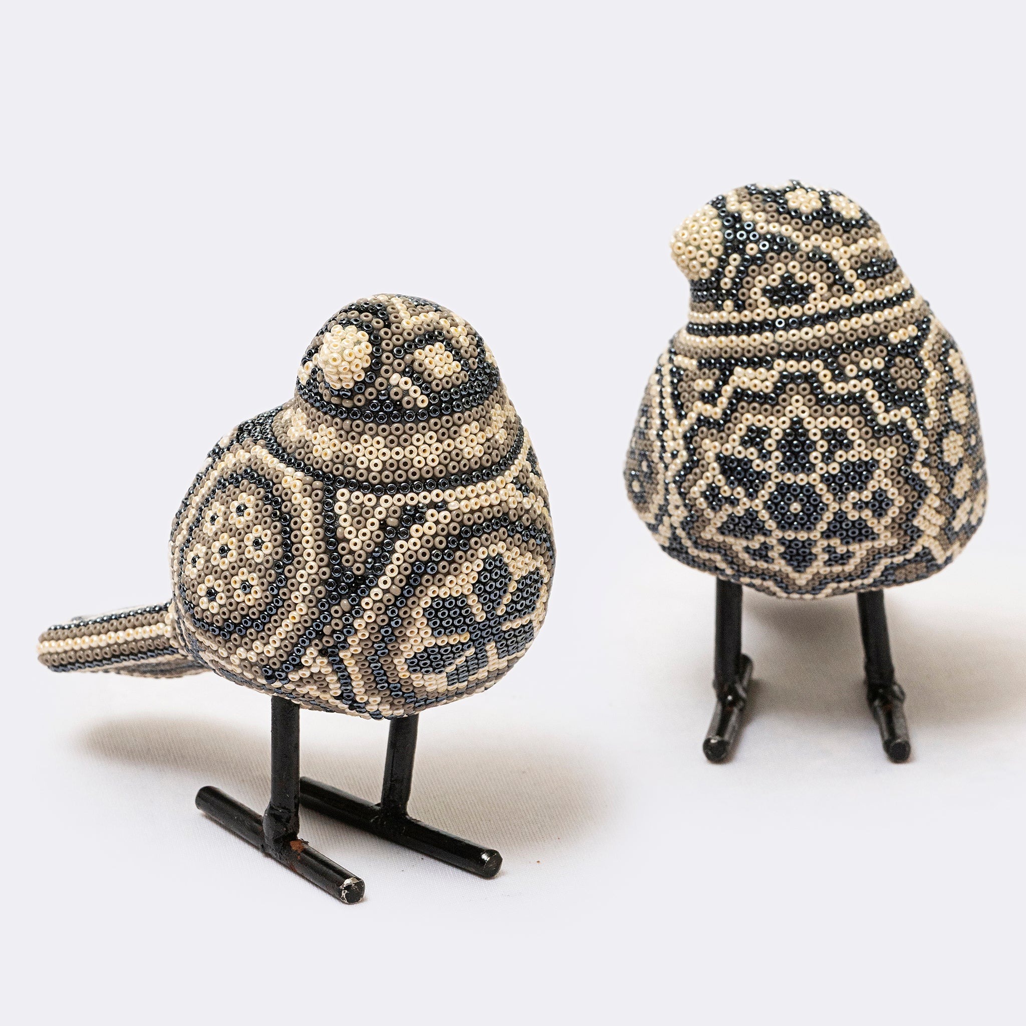 Two decorative birds made of beaded material on a white background