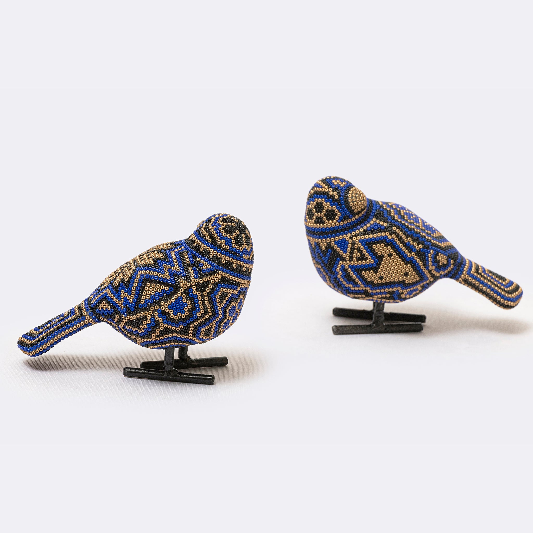 Two beaded bird figurines on stands against a white background