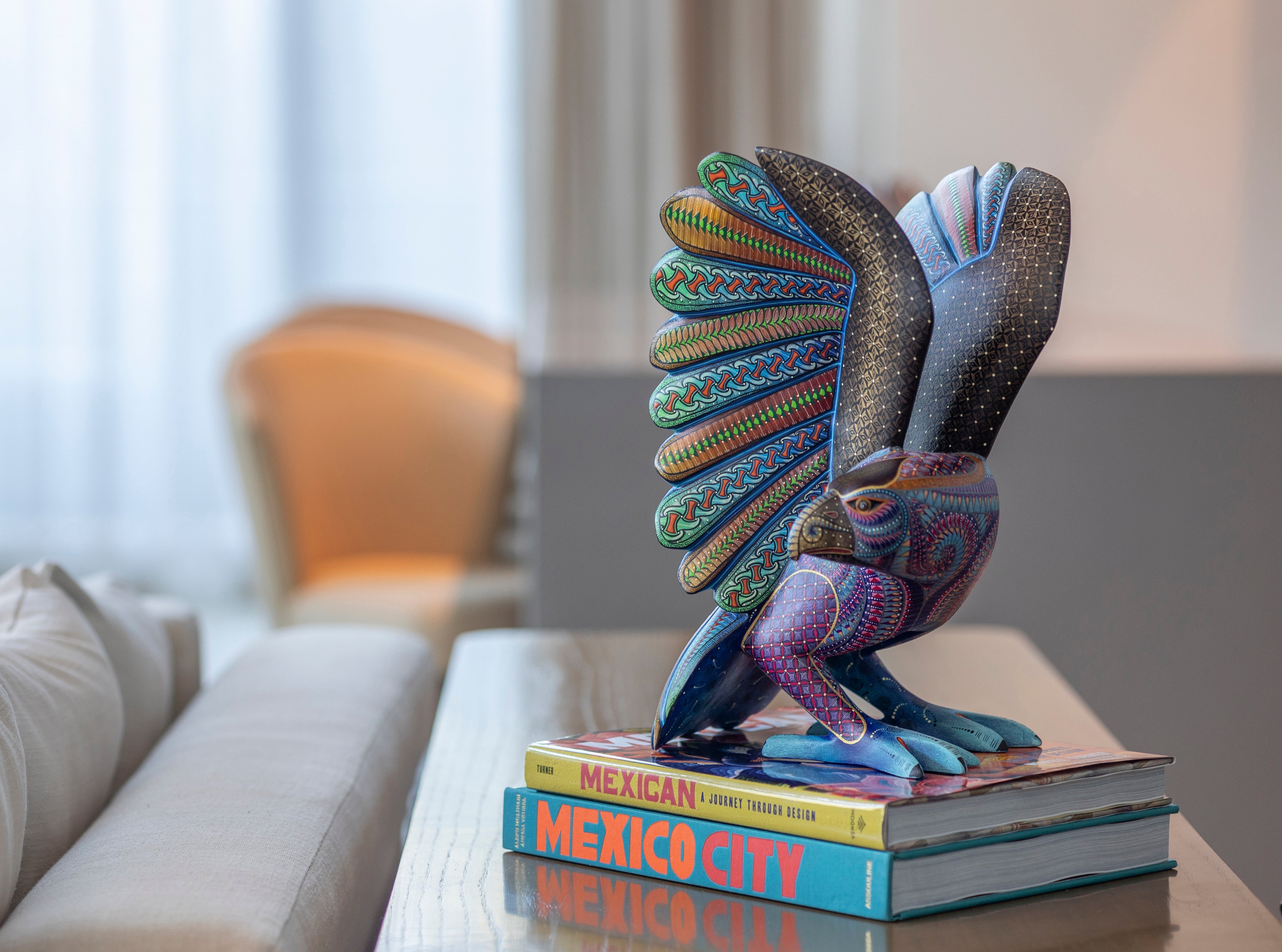 Colorful eagle figurine on books with a blurred indoor background