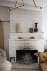 White brick fireplace with decorative items in a living room setting.
