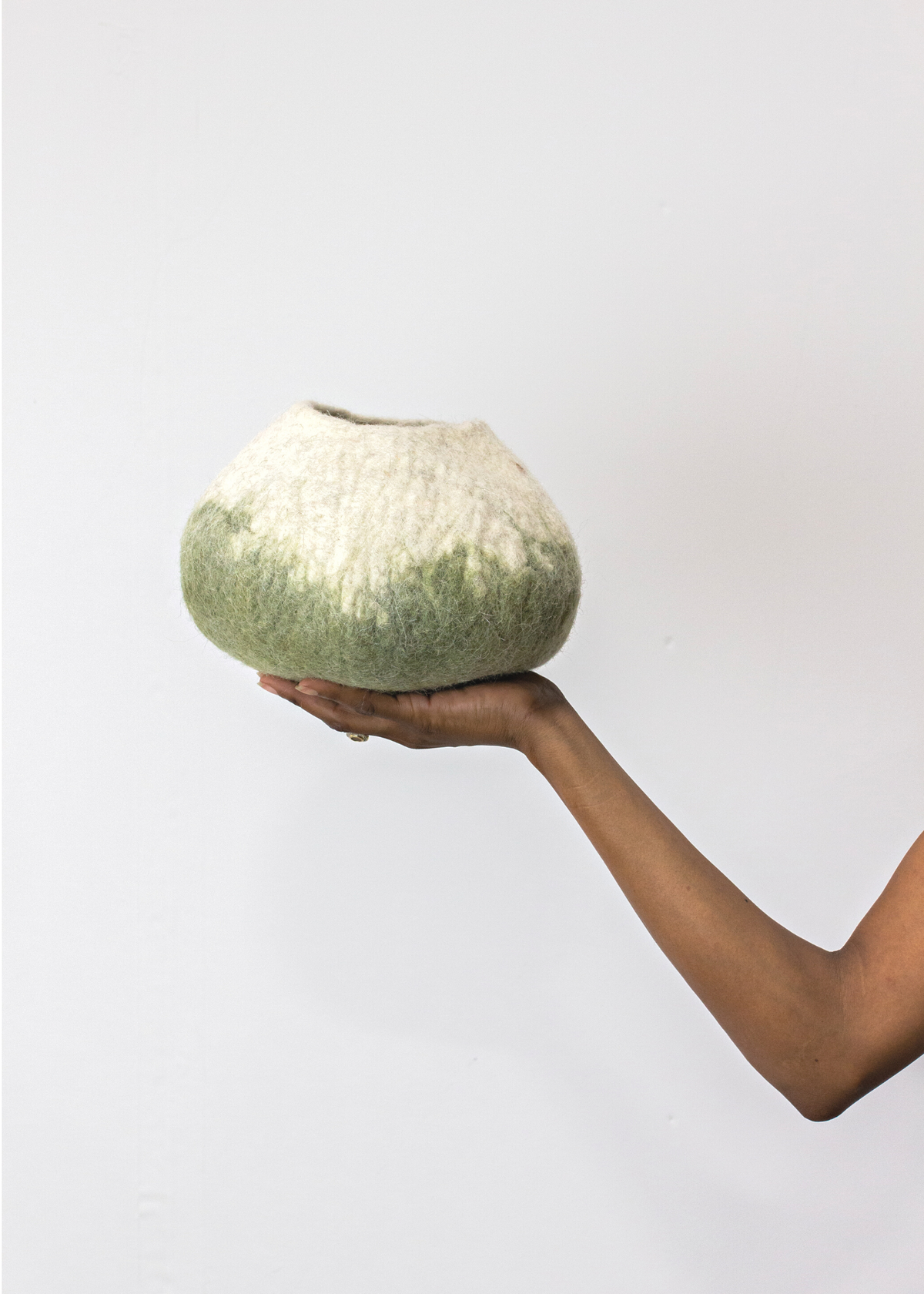 Hand holding a textured ceramic vase against a plain background