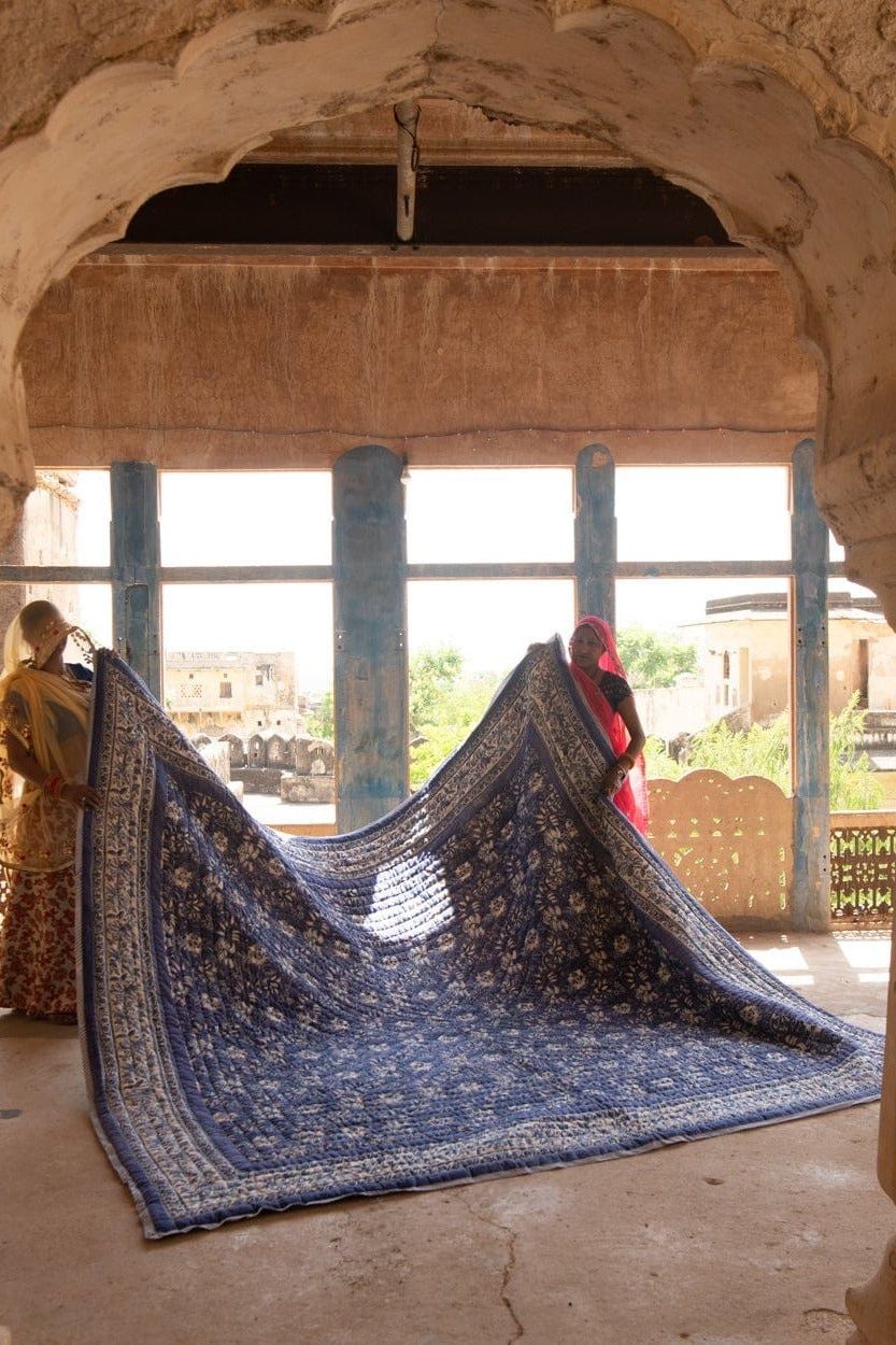 Large blue patterned rug displayed in a room with arched windows.