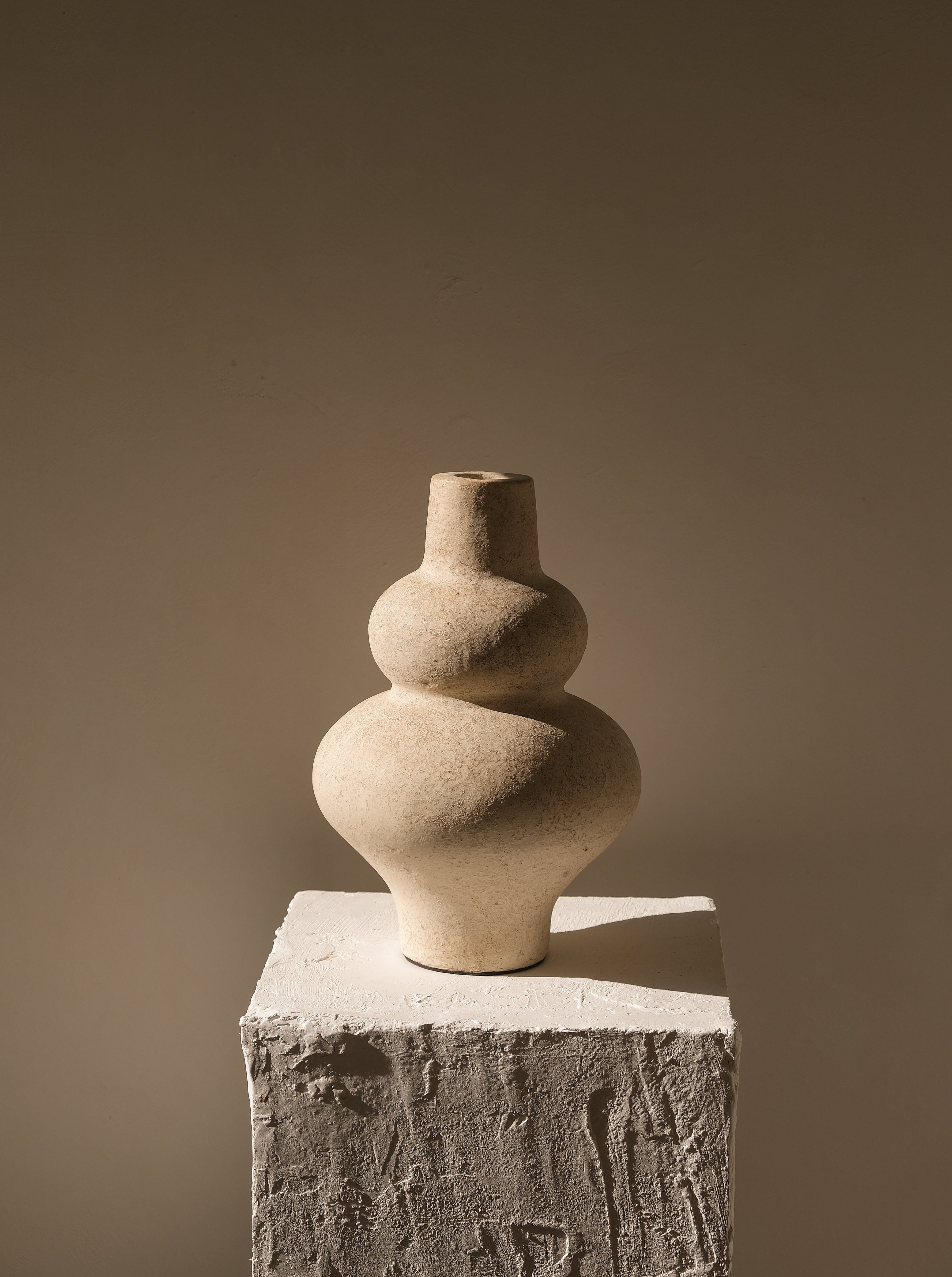 Stacked stone vases on a textured pedestal against a plain background