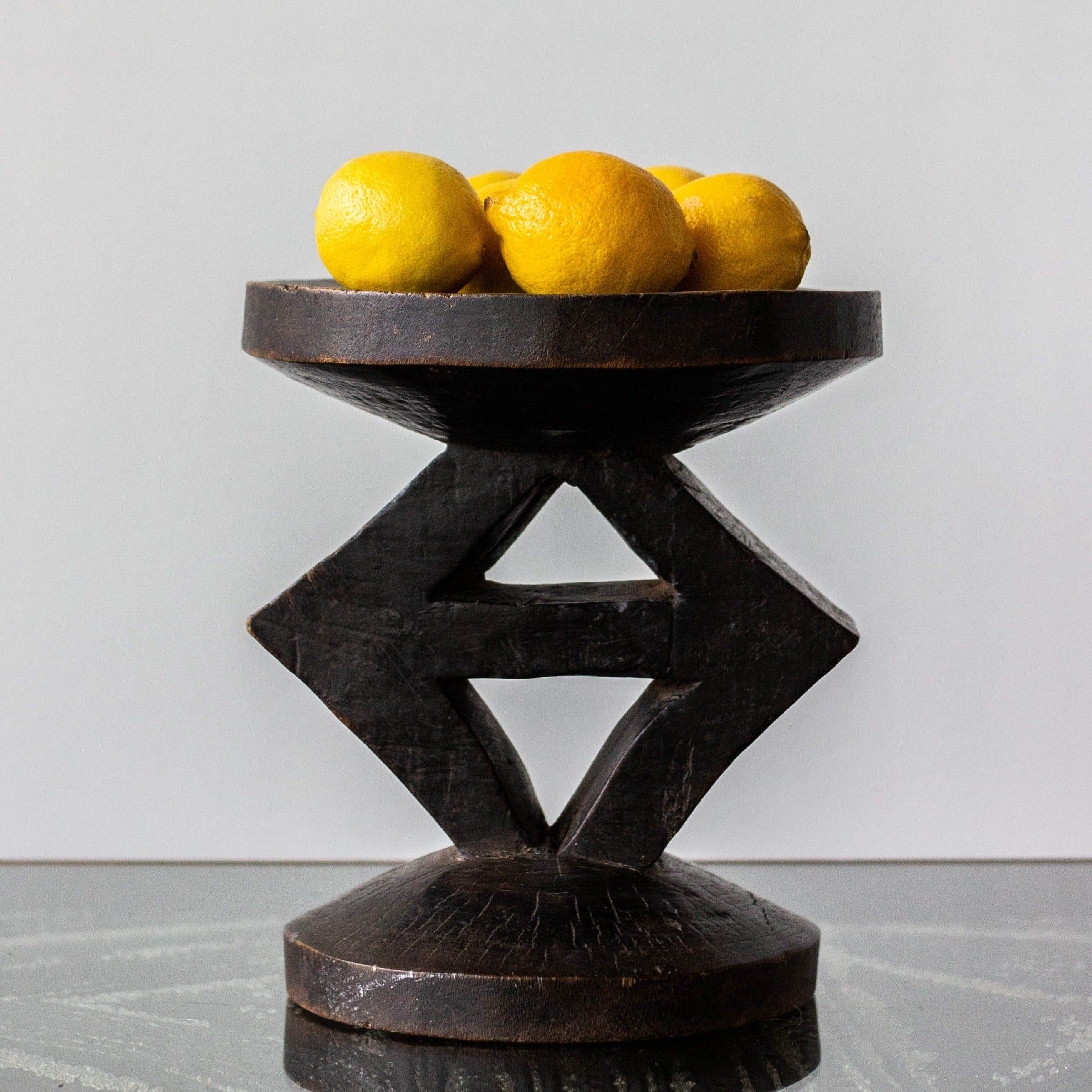 Decorative dark wood bowl with lemons on a light gray background